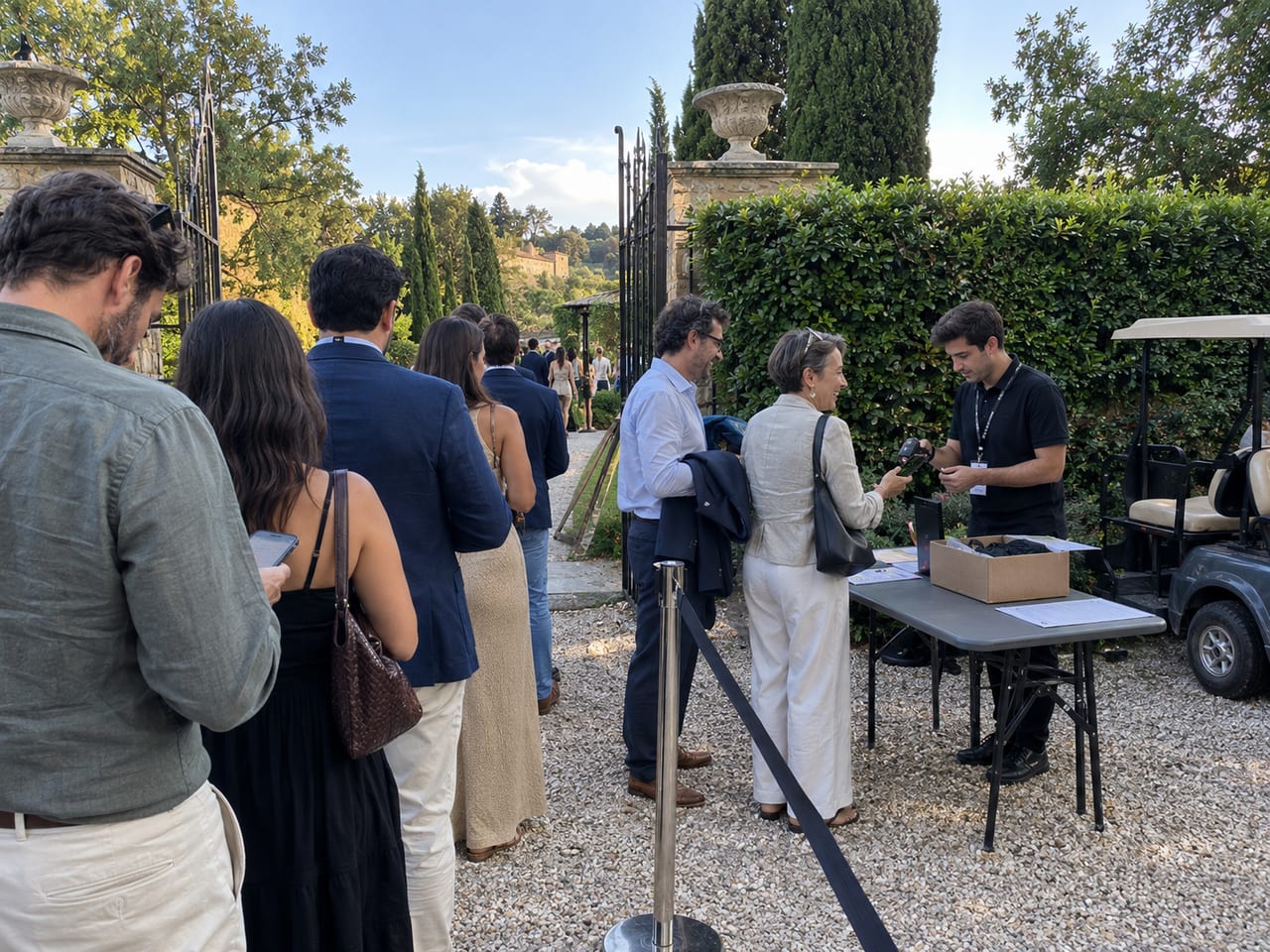 Guests queuing at a garden gate while a staff member scans a phone ticket